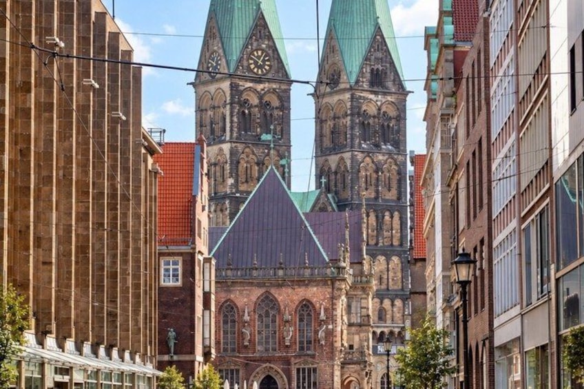 A historic church with two towers, a red-roofed building to the left, and a modern building to the right. 4