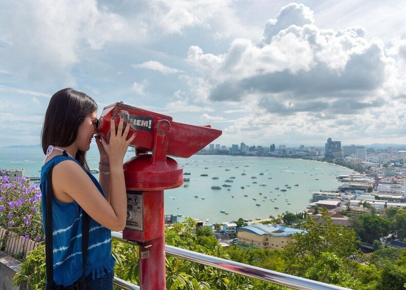 A person using a red binoculars, overlooking a coastal cityscape with boats and buildings. 3