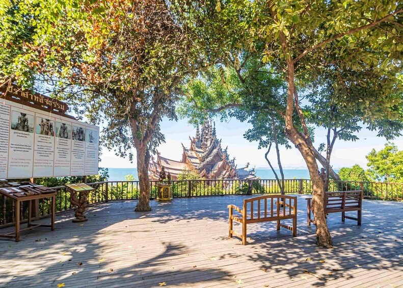 A wooden deck with benches, trees, and a traditional temple in the background. 4