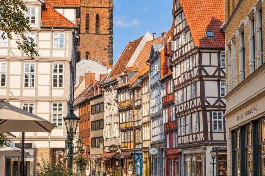 A street lined with traditional half-timbered buildings, a church tower, and a shop with a sign reading 'BUCHHANDLUNG'. 4