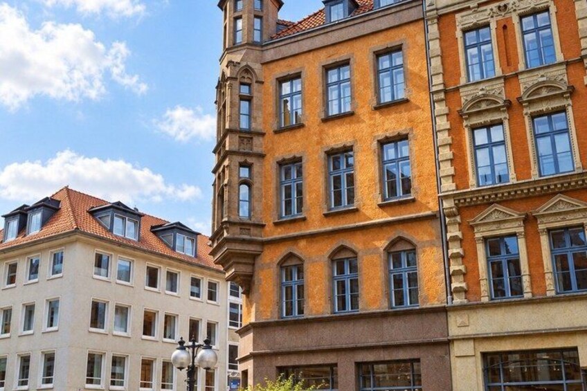 A multi-story building with a red-tiled roof and a corner tower. 5