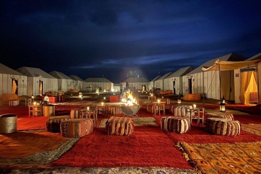 A series of tents with a central fire, surrounded by seating areas. 3