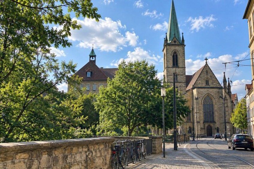 A street with a church, stone wall, and bicycles. 5