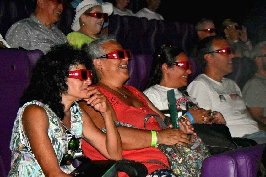 Personas sentadas en un auditorio con asientos morados. 5