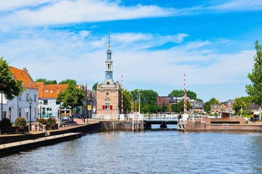 A canal with a bridge, a church tower, and buildings along the water's edge. 3