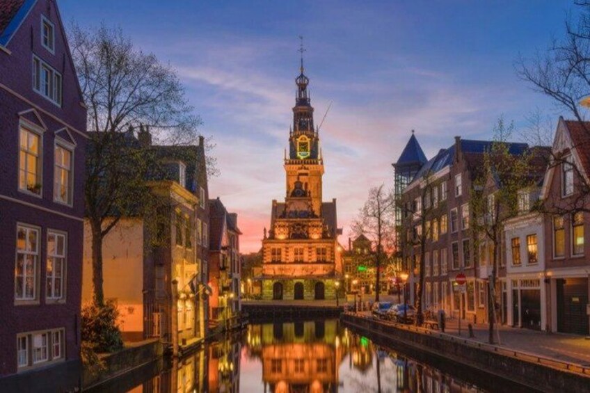 A canal with buildings on either side, a prominent clock tower, and a sunset sky. 2