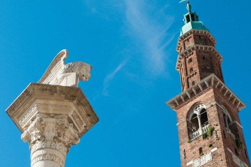 A stone angel statue and a brick tower against a clear blue sky. 2