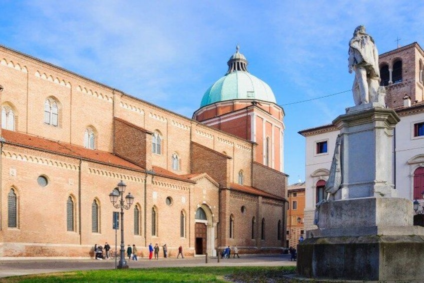 A historic building with a dome, a statue, and people walking in the foreground. 4
