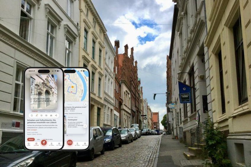 A cobblestone street lined with historic buildings, a parked bus, and a smartphone displaying a map. 1