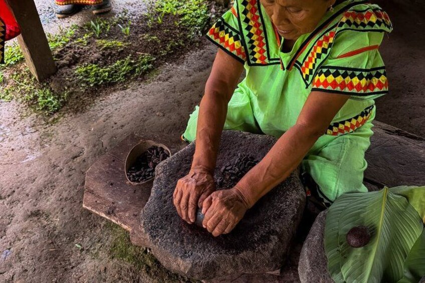 A person using a stone mortar and pestle outdoors. 1