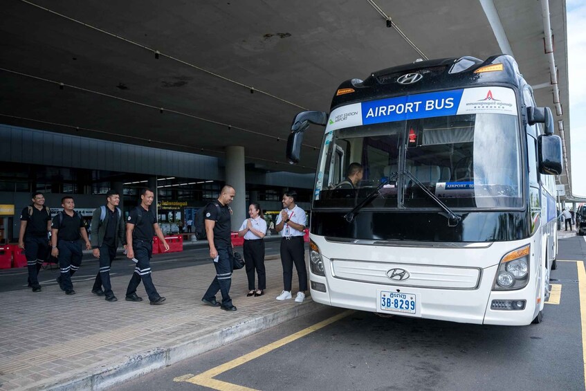 An airport bus with passengers boarding at an airport terminal. 3