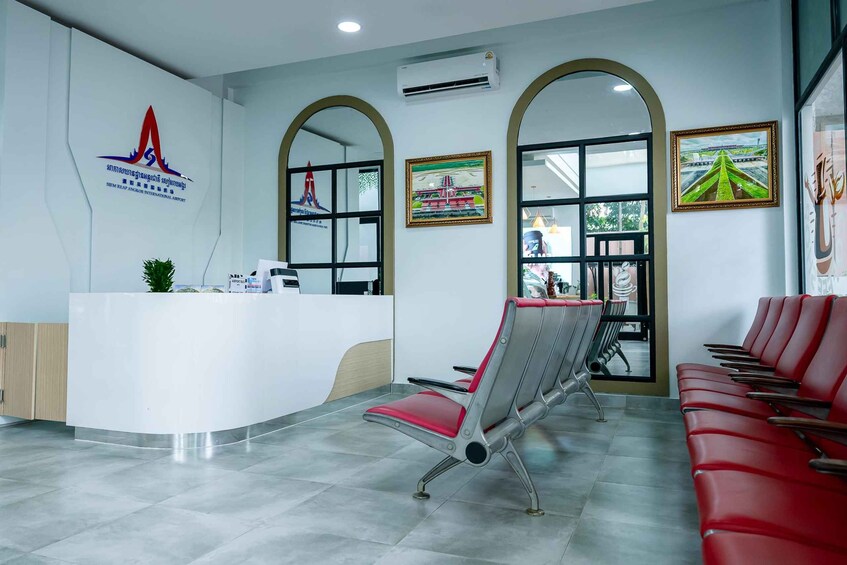 A reception area with a white counter, red chairs, and framed artwork on the walls. 2
