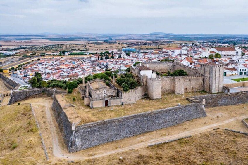 A fortified town with historic walls and buildings, surrounded by open fields. 2
