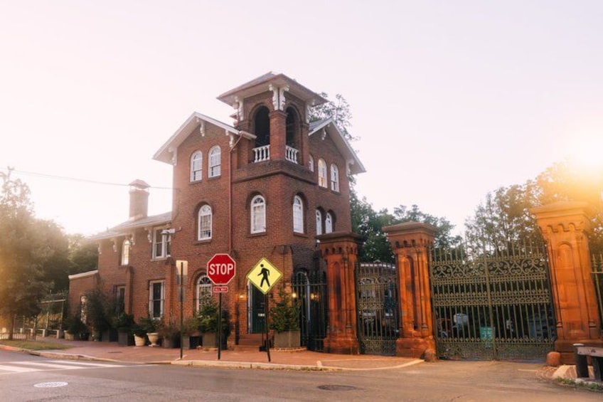 A historic brick building with a stop sign, pedestrian crossing, and ornate iron gates. 2