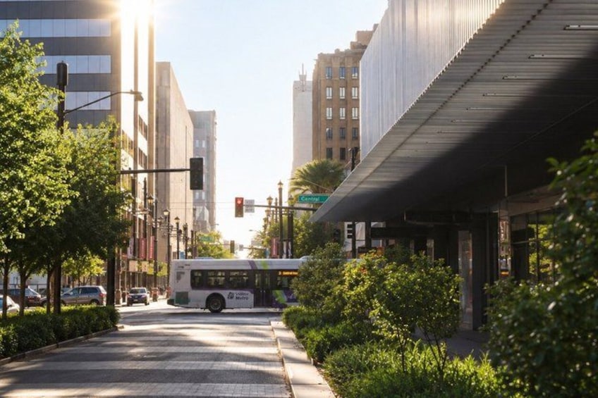 A city street with a bus, buildings, and greenery. 3
