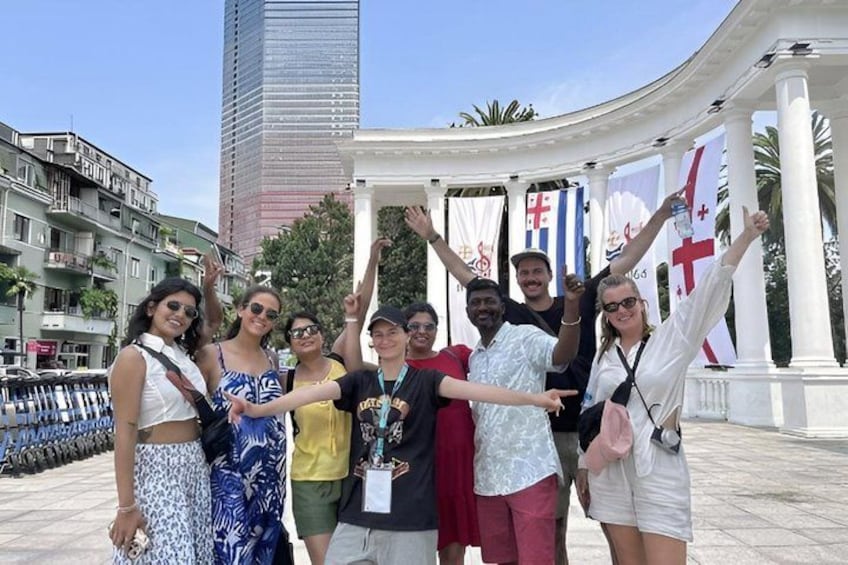 A group of people posing in a plaza with flags and a tall building in the background. 2