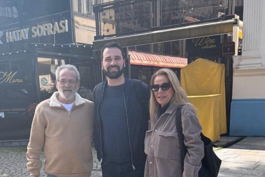 Three people standing in front of a building with a sign that reads 'Hatay Sofrasi.' 5