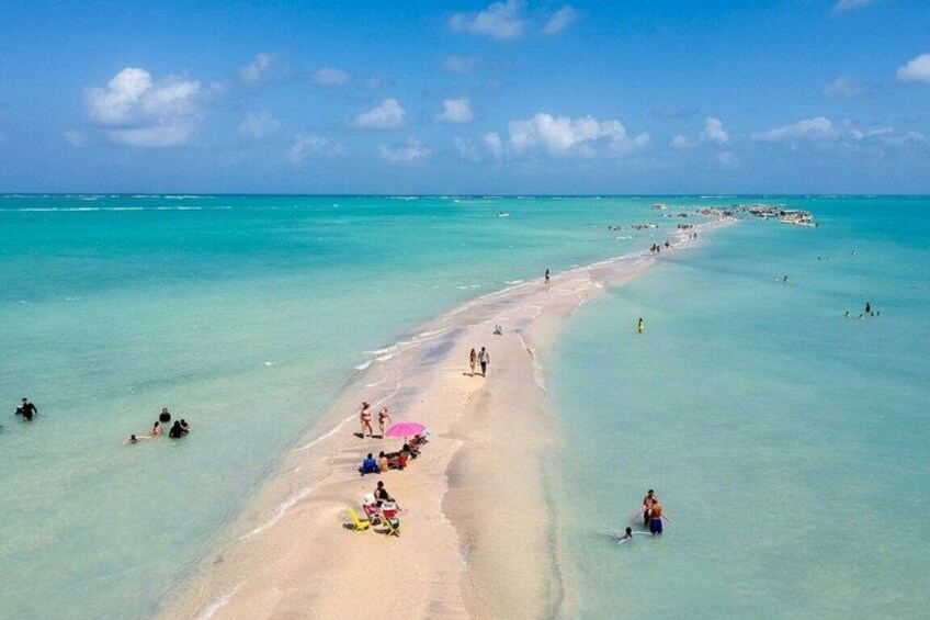 A beach with clear turquoise water, people sunbathing, and a few umbrellas. 2