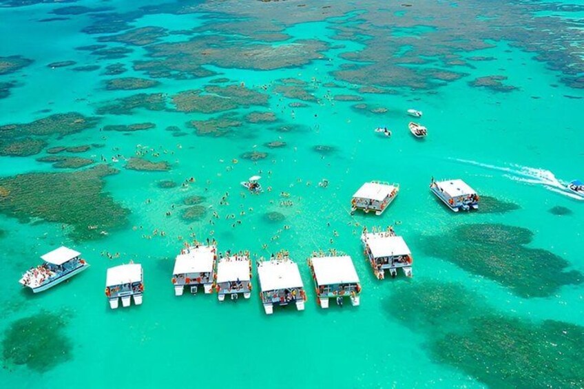 A turquoise sea with boats and people. 3