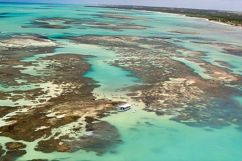 A coastal area with clear turquoise waters, sandy beaches, and a boat anchored near the shore. 1