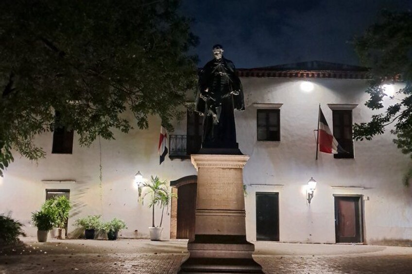 A statue on a pedestal in front of a building with flags. 5