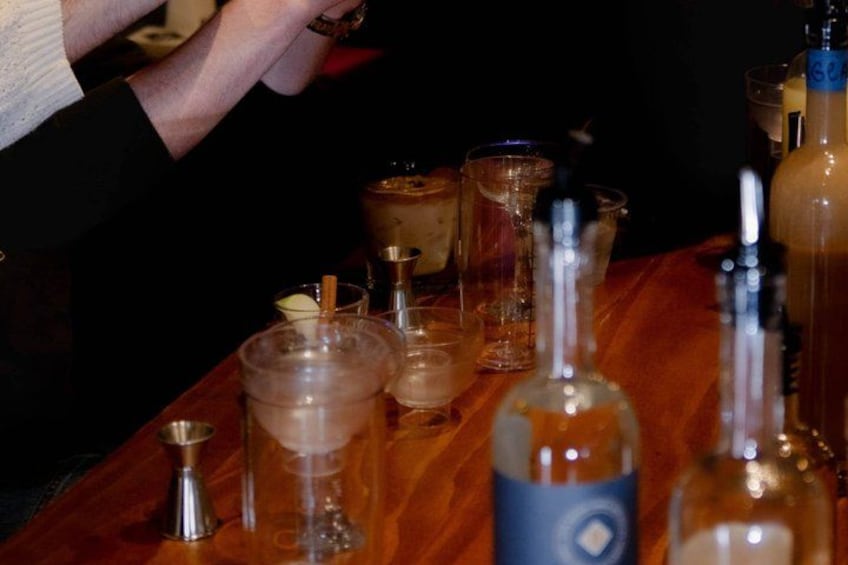 A bar setting with various bottles and glasses on a wooden table. 4