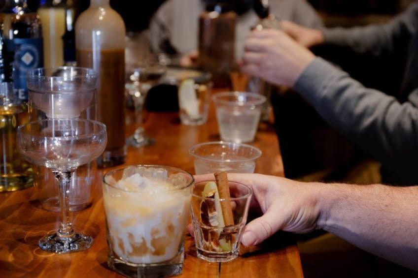 A bar setting with various glasses of beverages, ice cubes, and a bottle. 3
