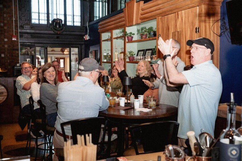 A group of people in a bar with wooden walls and shelves of bottles. 1