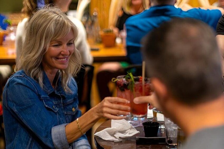 A person holding a drink with a straw, sitting at a table with a napkin and a small cup. 5