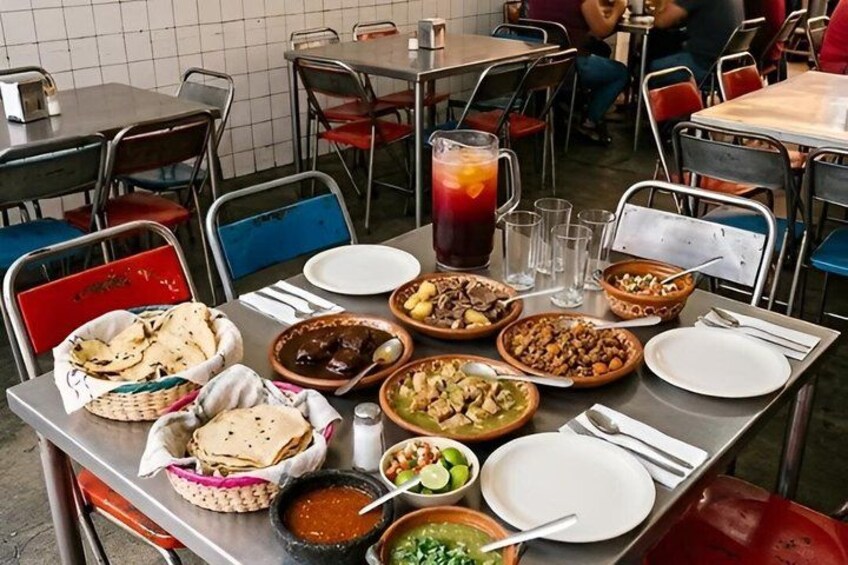 A dining table with various dishes, including bowls of food, a pitcher of iced tea, and plates. 3
