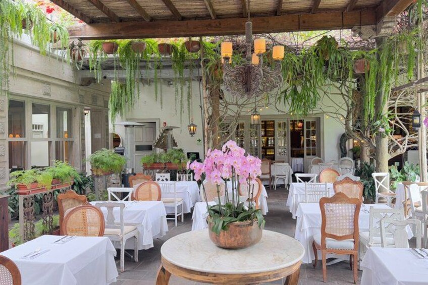 An outdoor café with tables and chairs, surrounded by hanging plants and greenery. 3