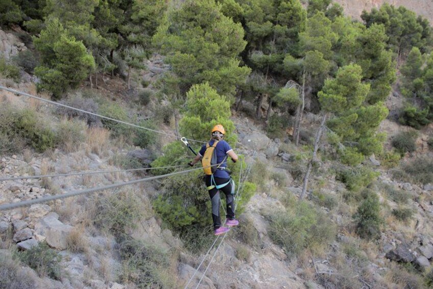 A person zip-lining across a rocky terrain with sparse vegetation. 4
