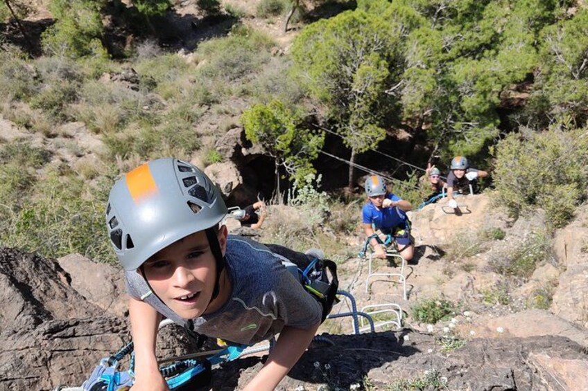 A person in a helmet climbing a rocky terrain with trees in the background. 5