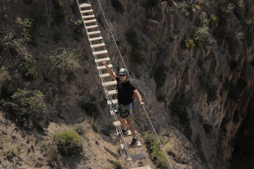 A person on a rope bridge over a canyon. 2