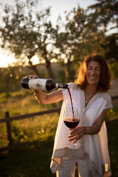 A person pouring red wine from a bottle into a glass. 3