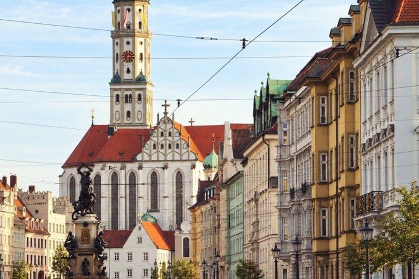 A historic church with a tall tower, colorful buildings, and statues. 3