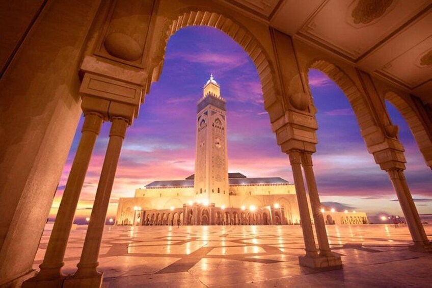 A historical building with arches and a tower, under a twilight sky. 3