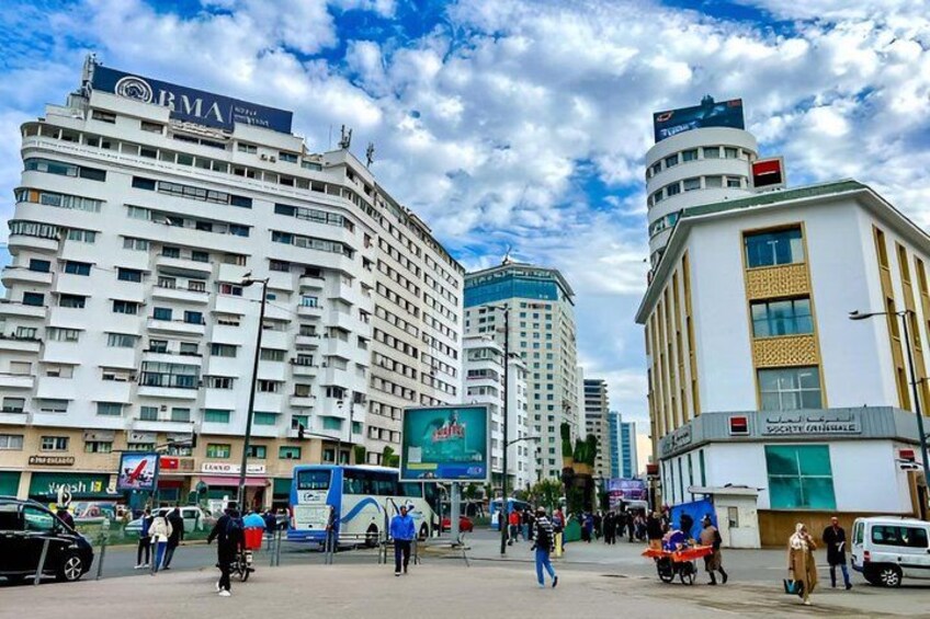 A busy urban street with modern buildings, a bus, and pedestrians. 2