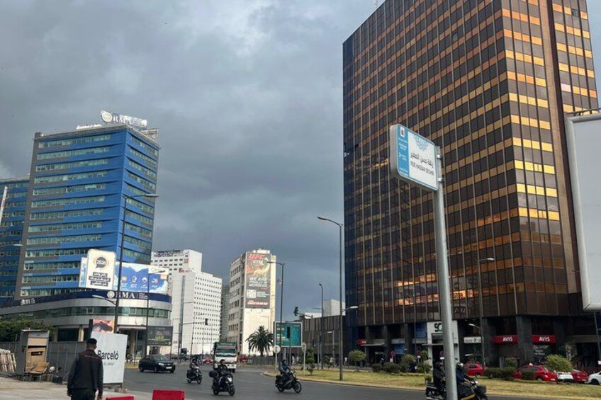 A cityscape with tall buildings, a street with vehicles, and a signpost. 5