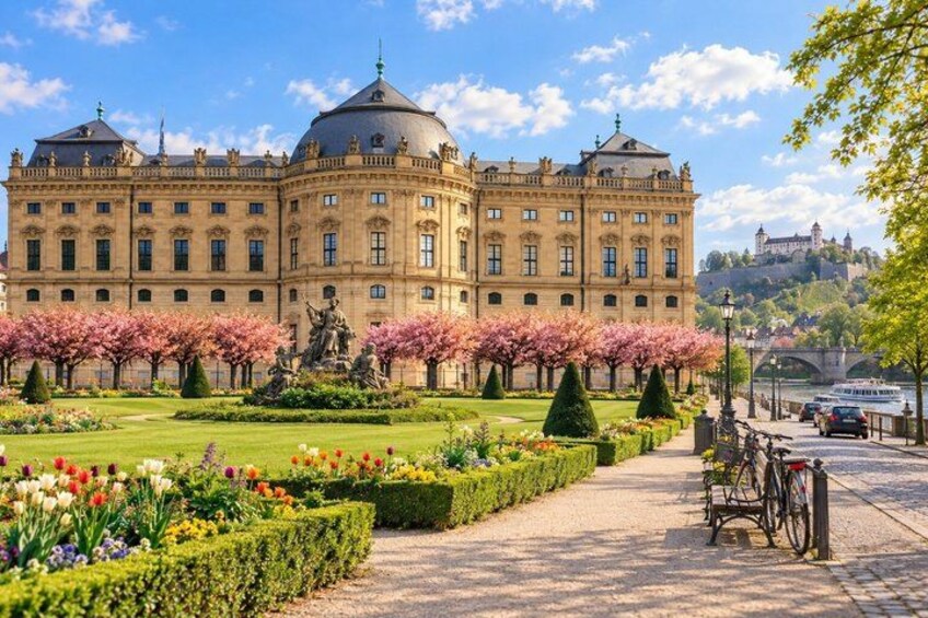 A historic building with a garden, a statue, and a bridge in the background. 3