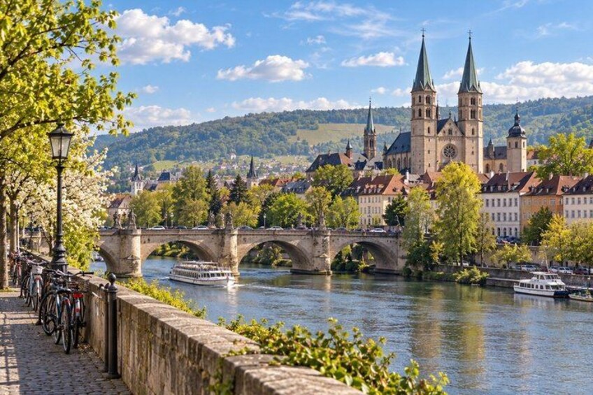 A river with a bridge, a boat, and a historic church with two towers. 4