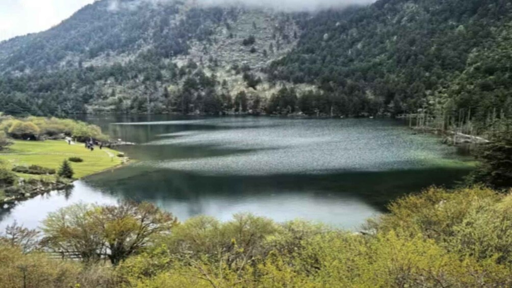 A lake surrounded by forested mountains, with a clear sky above. 2
