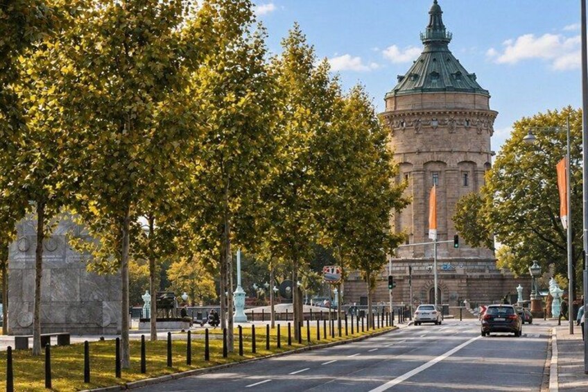 A street lined with trees, a historic tower, and a monument. 2
