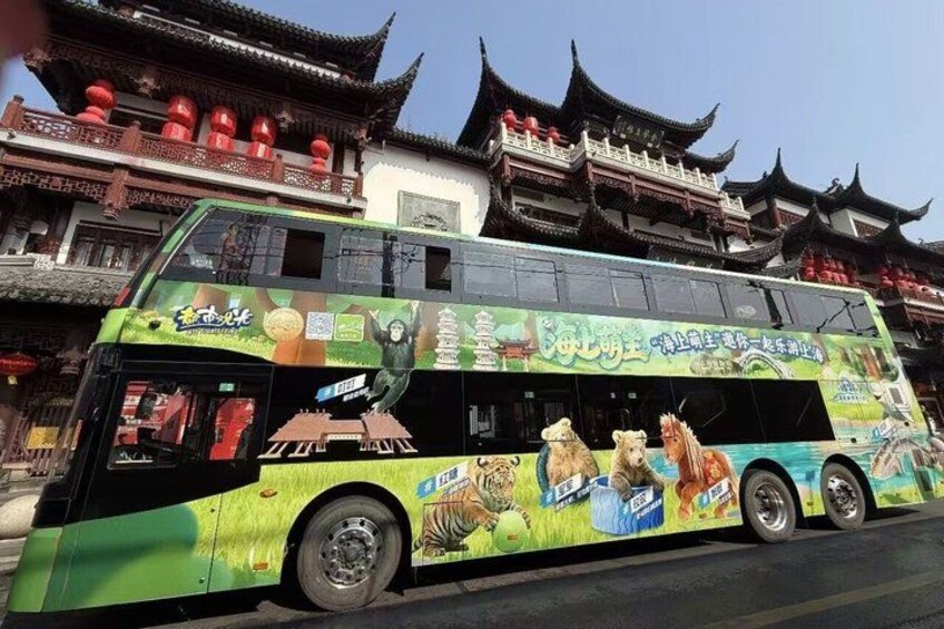 A double-decker bus with animal illustrations and text, parked in front of traditional Chinese architecture. 3