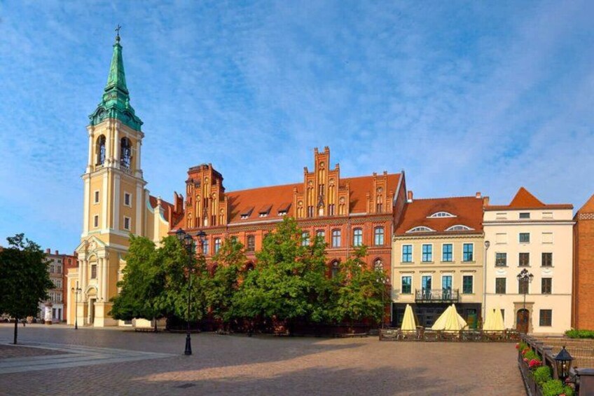 A historic building with a clock tower, a red brick structure, and a white building with a green roof. 4