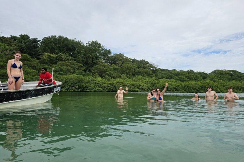 A group of people in a boat and in the water, surrounded by lush greenery. 4