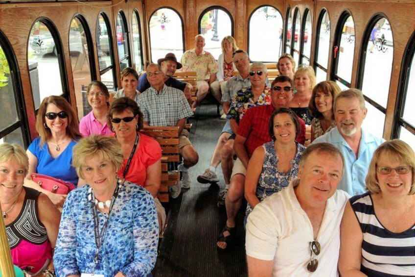 A group of people seated inside a bus with arched windows. 5