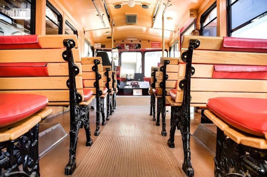A bus interior with wooden benches and red seats. 4