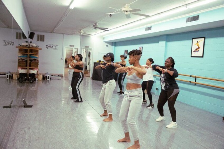 A dance class in a studio with mirrors, barre, and a ceiling fan. 4