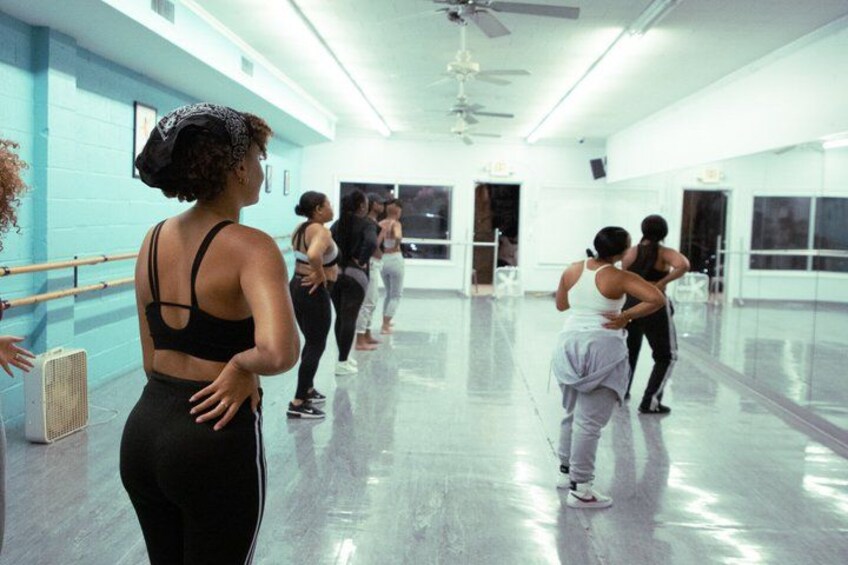 A dance studio with a polished floor, mirrors, and ballet barres along the walls. 5